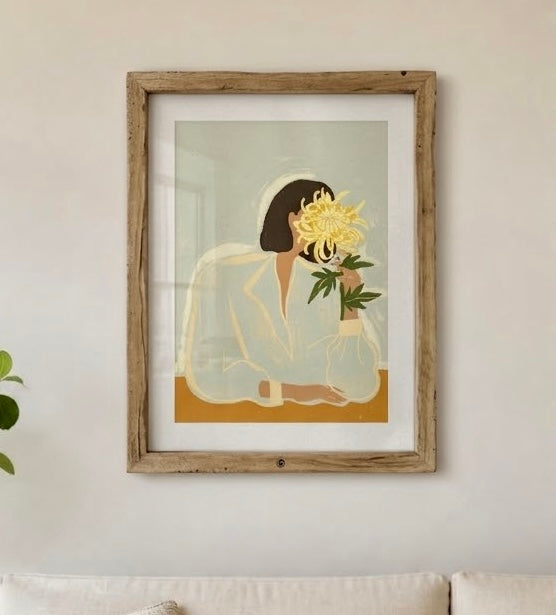Affiche portrait floral encadrée sur un mur de salon, vue rapprochée du chrysanthème jaune et de la chemise crème