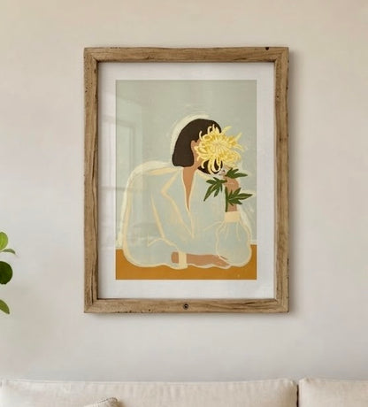 Affiche portrait floral encadrée sur un mur de salon, vue rapprochée du chrysanthème jaune et de la chemise crème