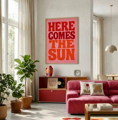 Poster typographique Here Comes The Sun rose et rouge encadré sur le mur d'un salon