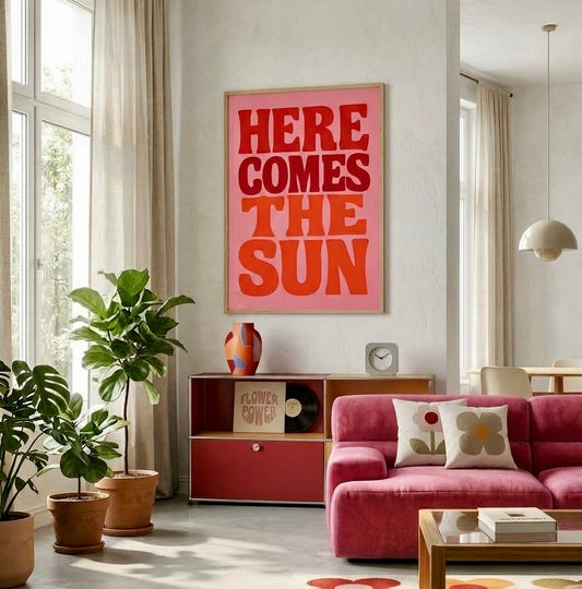 Poster typographique Here Comes The Sun rose et rouge encadré sur le mur d'un salon